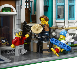 LEGO figures in a city street scene with buildings and a storefront.