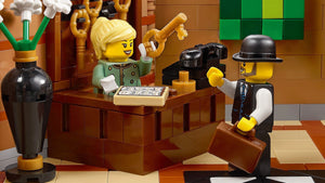 LEGO figures in a scene with a desk and various items on a checkered floor.