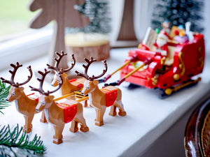 Toy reindeer pulling a toy sleigh with Santa Claus on a windowsill.