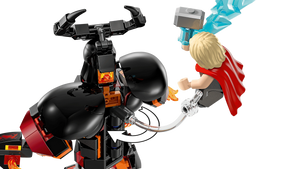 Toy figure of a superhero in a red cape swinging on a rope from a black mechanical dragon-like creature.