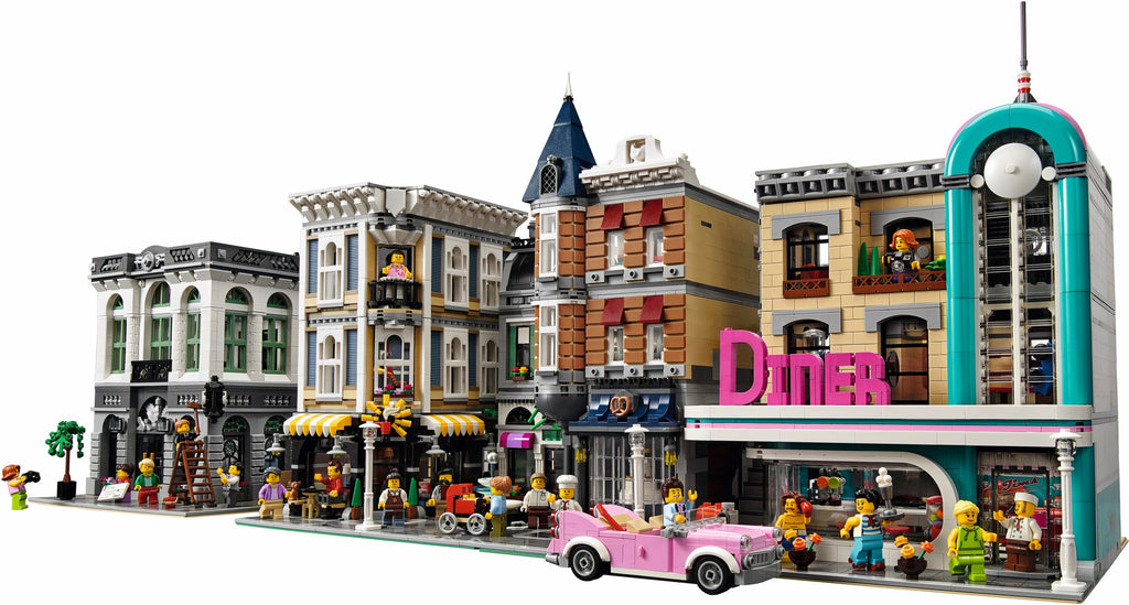 LEGO model of a city street with buildings and a pink car.