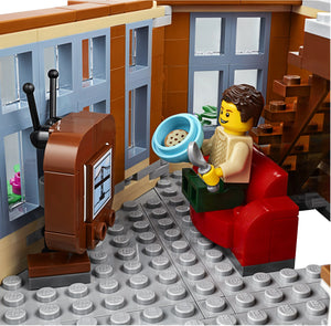 LEGO figure sitting on a red couch with a TV and cookie in a bowl.