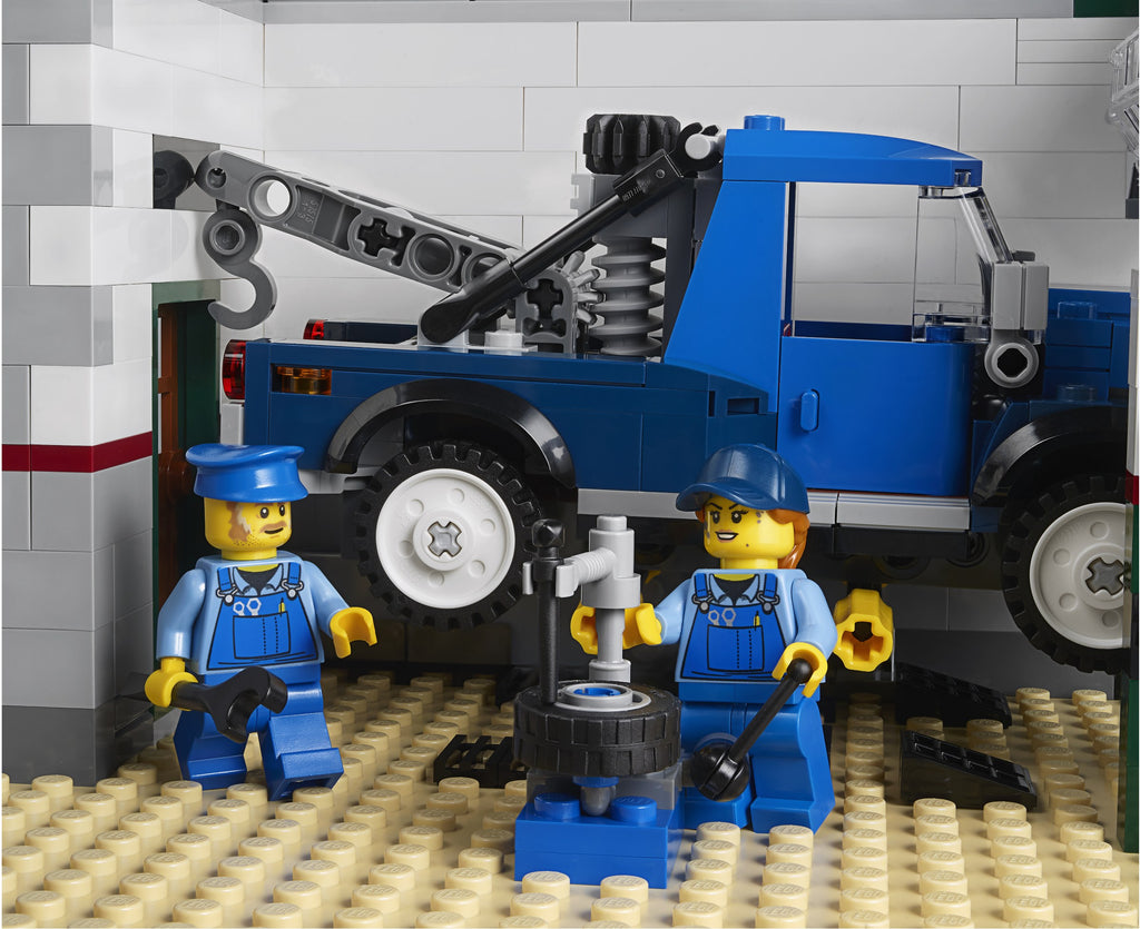 LEGO tow truck and mechanics set against a gray tiled wall.