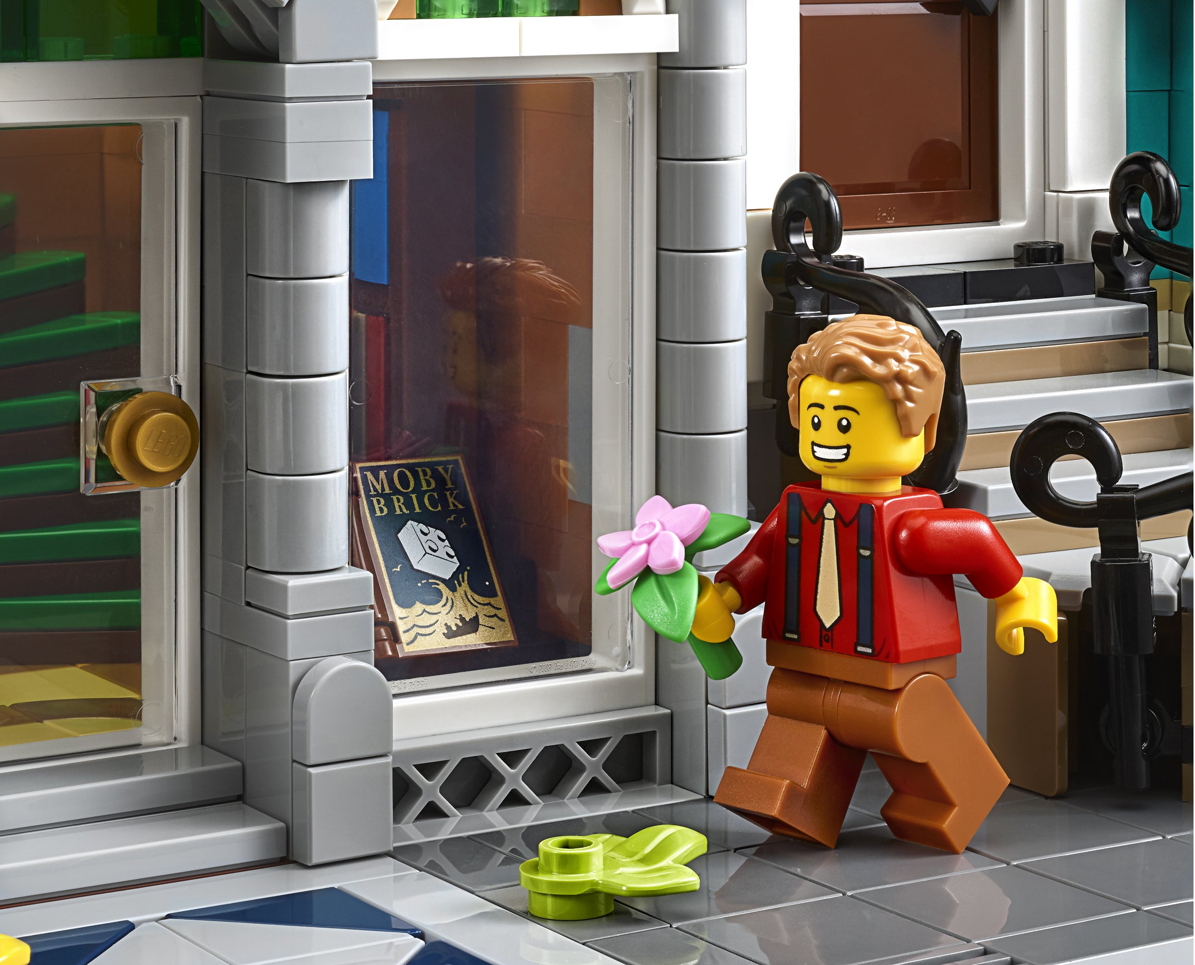 LEGO figure holding a flower in front of a store window