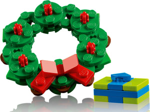 Christmas wreath made of green building blocks with red details and a blue gift box on a white background