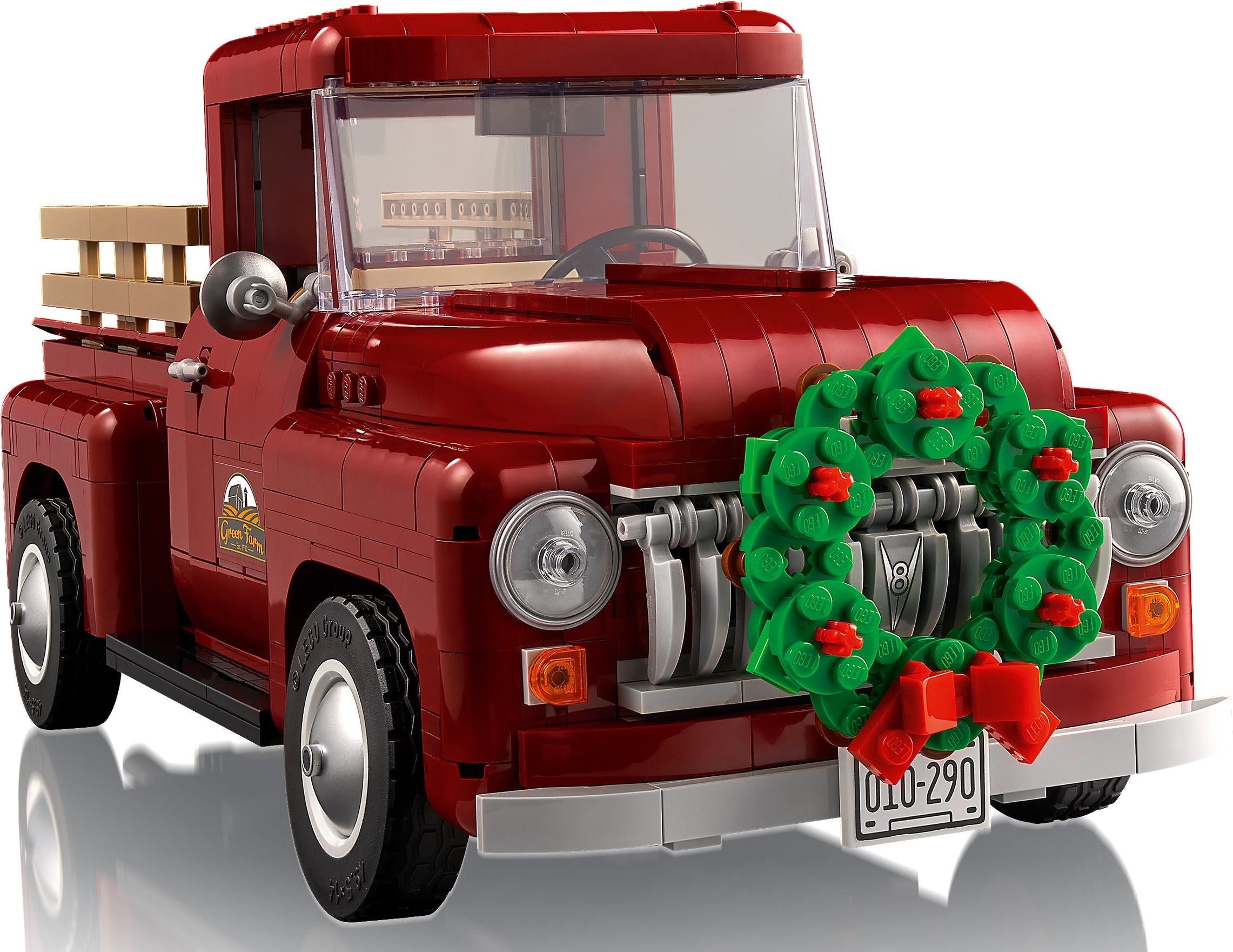 Red toy truck with a Christmas wreath on a white background