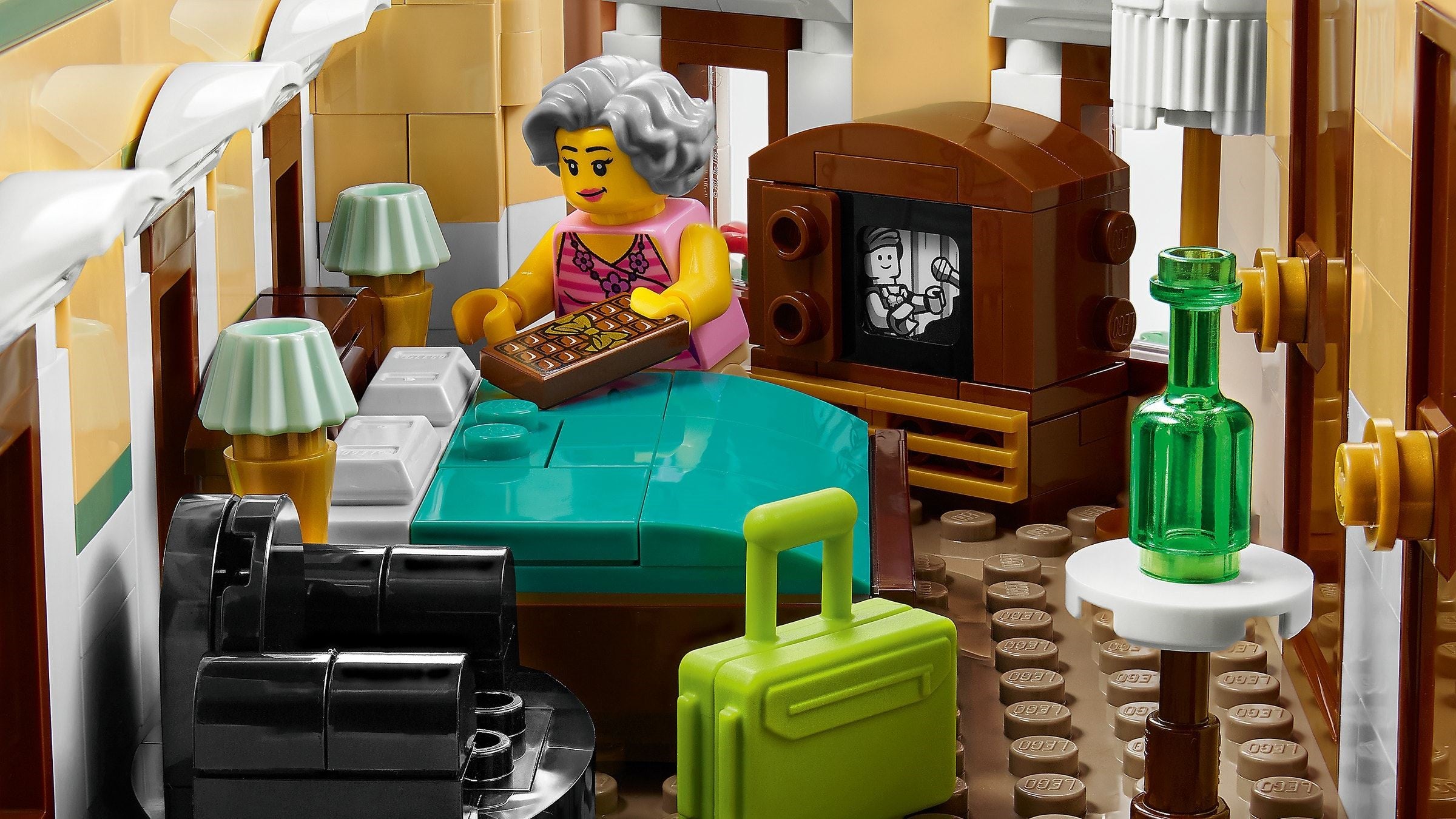 LEGO set of a living room with furniture and a person sitting at a table.