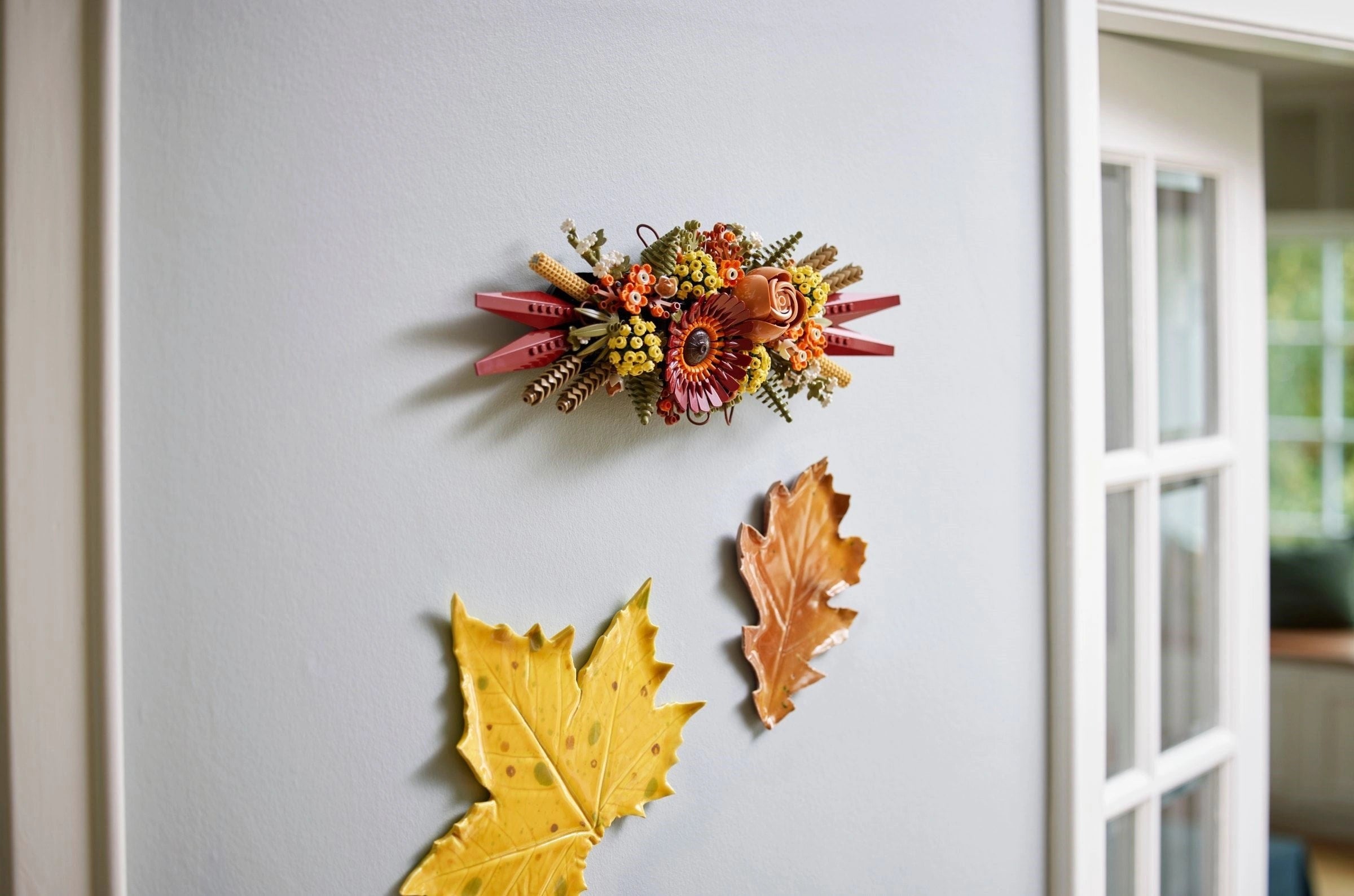 Decorative wall piece with autumn-themed elements on a light gray wall.