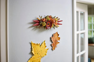Decorative wall piece with autumn-themed elements on a light gray wall.