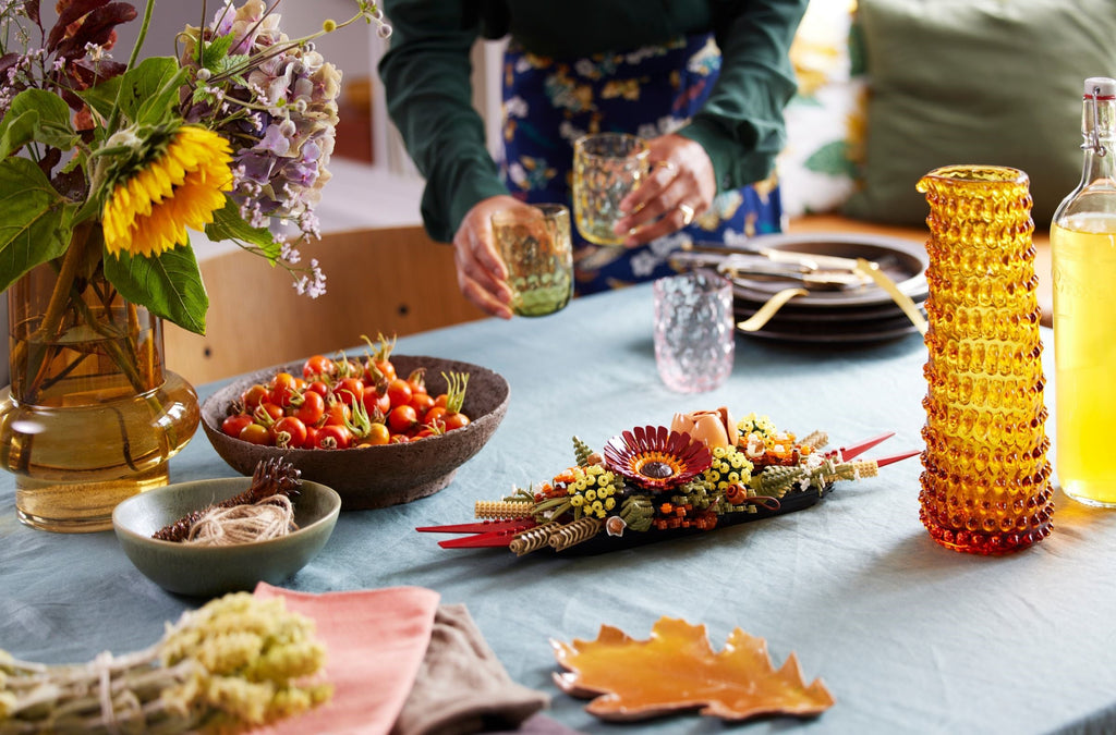 Decorative table setting with flowers, food, and decorative items on a blue tablecloth.
