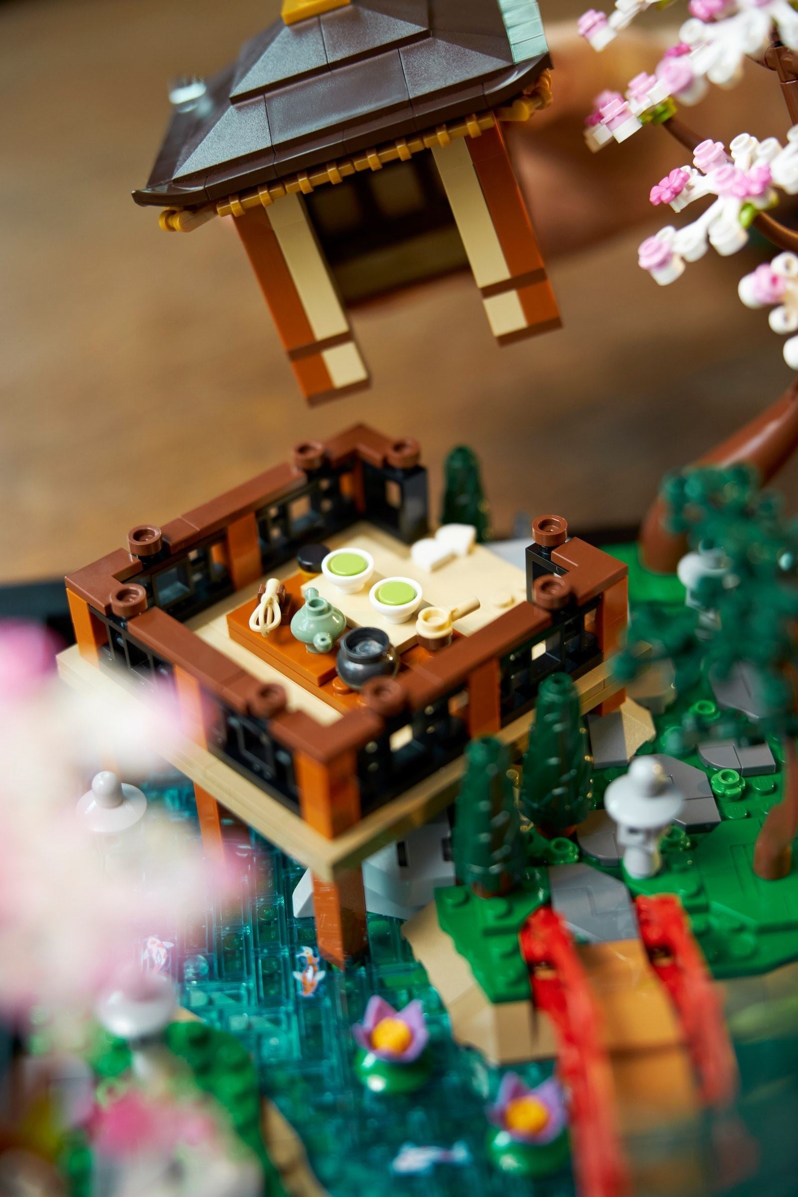 Close-up of a detailed LEGO model with a pagoda, table, and cherry blossoms.