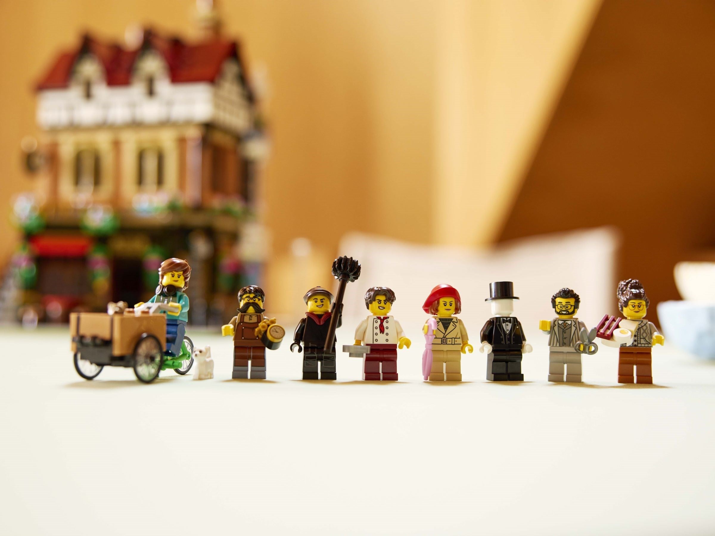 Row of LEGO figures in front of a blurred LEGO house model.