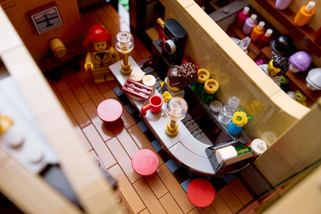 Toy kitchen set with LEGO figures and furniture, including a refrigerator, stove, and dining table.