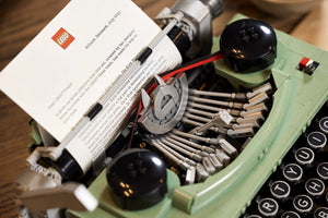 Green typewriter with a LEGO book on a wooden surface