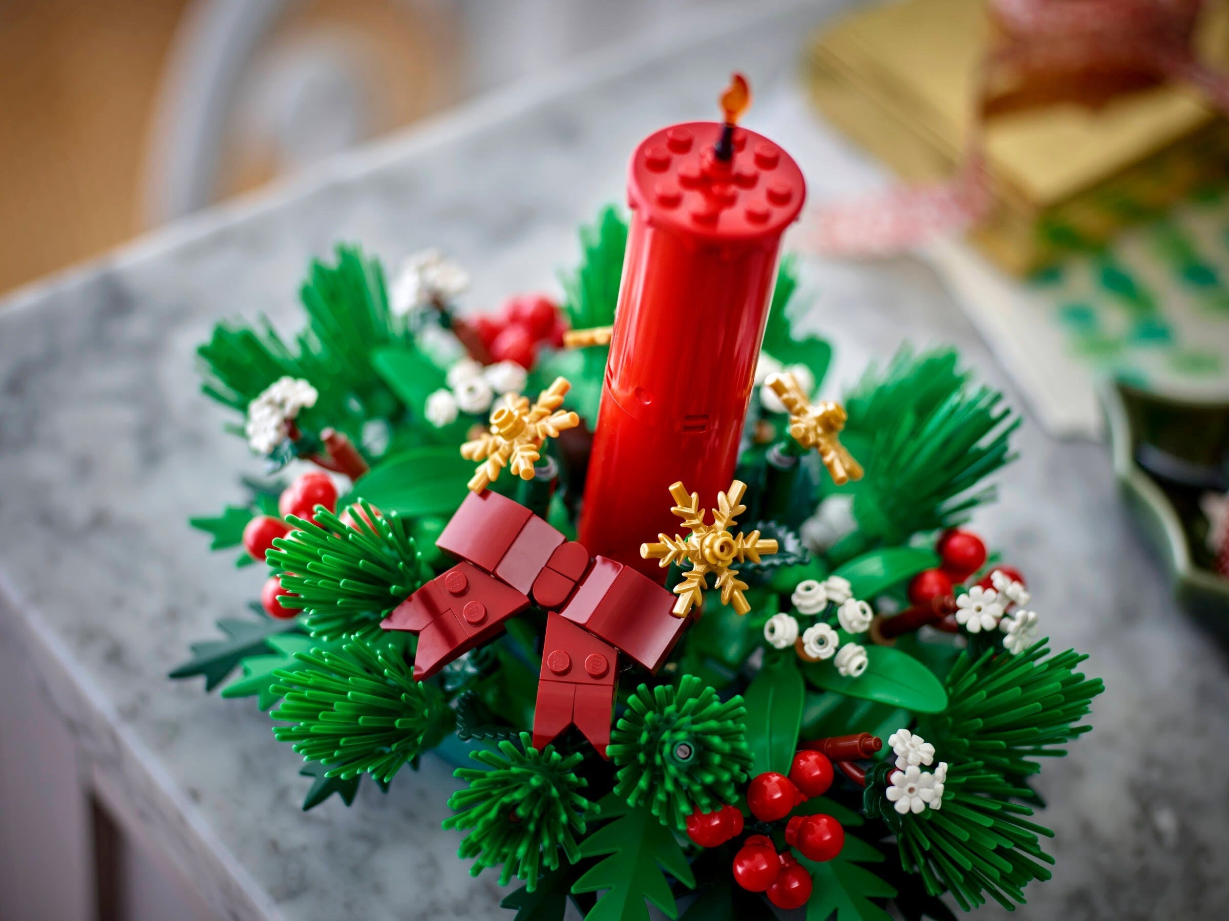 Christmas wreath made of LEGO bricks with a red candle on a marble surface.